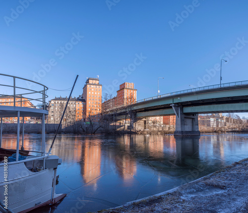 View over the canal Karlbergskanalen with ice floes and an old boat, apartment houses and the bridge St Eriksbron with tower houses a winter day in Stockholm