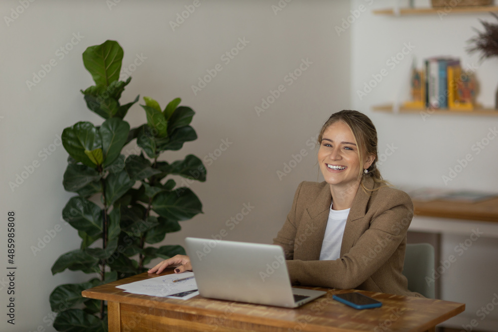 Young woman working at home with laptop and papers on desk and headphones. Home office concept.