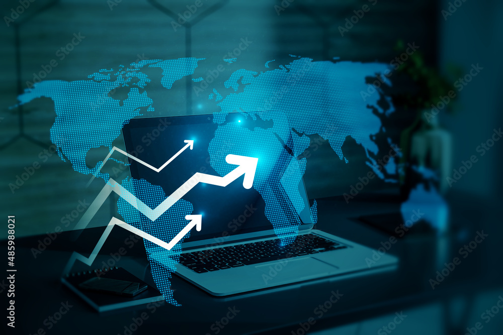 Close up of office desktop with laptop computer and abstract glowing growing business arrow and map hologram on blue background. Technology and internet data concept. Double exposure.