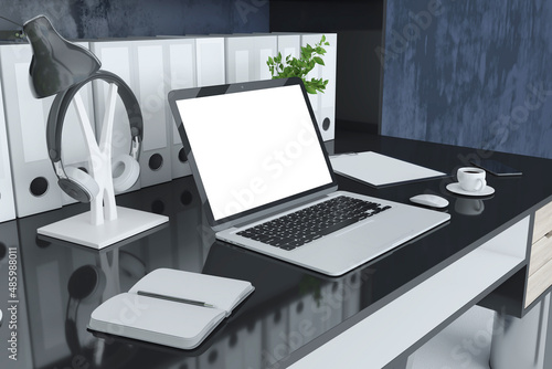 Close up of modern designer workspace with folders bookcase, empty laptop screen, coffee cup, decorative plant and other items. Mock up, 3D Rendering.
