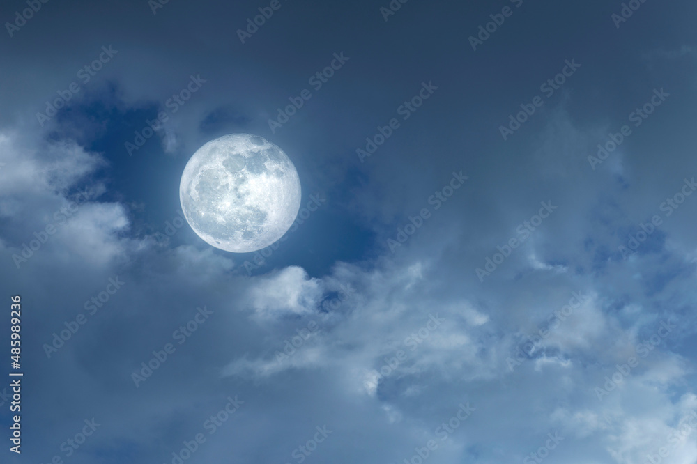 Amazing night sky with shining full moon and dramatic clouds