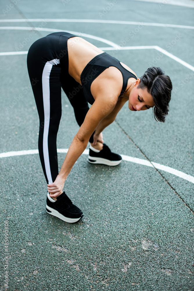 A Attractive caucasian woman with short hair doing stretching exercises on a sports court A Attractive caucasian woman with short hair doing stretching exercises on a sports court
