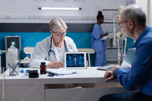 Medic showing tablet with illustration of human body analysis to senior man. Healthcare specialist explaining diagnosis to ill patient while holding device with virtual anatomy and expertise