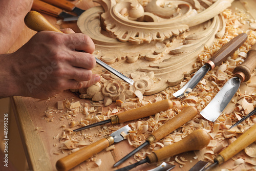 Wood carving. Carpenter's hands use chiesel. Senior wood carving professional during work. Man working with woodcarving instruments photo