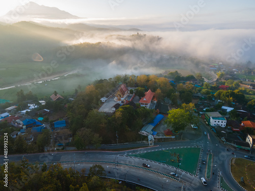 Aerial view of Red temple on top of the hill at the center of the town with foggy covers the mountains at the background, The northern villages are beautiful as an unseen travel attraction of Thailand