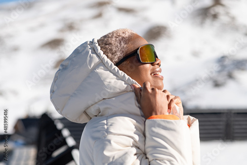 A African American woman wearing goggles standing in snowy mountain during winter

