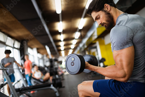 Muscular bodybuilder handsome man doing exercises in gym. Sport people workout concept