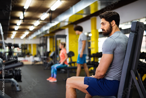 Muscular bodybuilder handsome man doing exercises in gym. Sport people workout concept