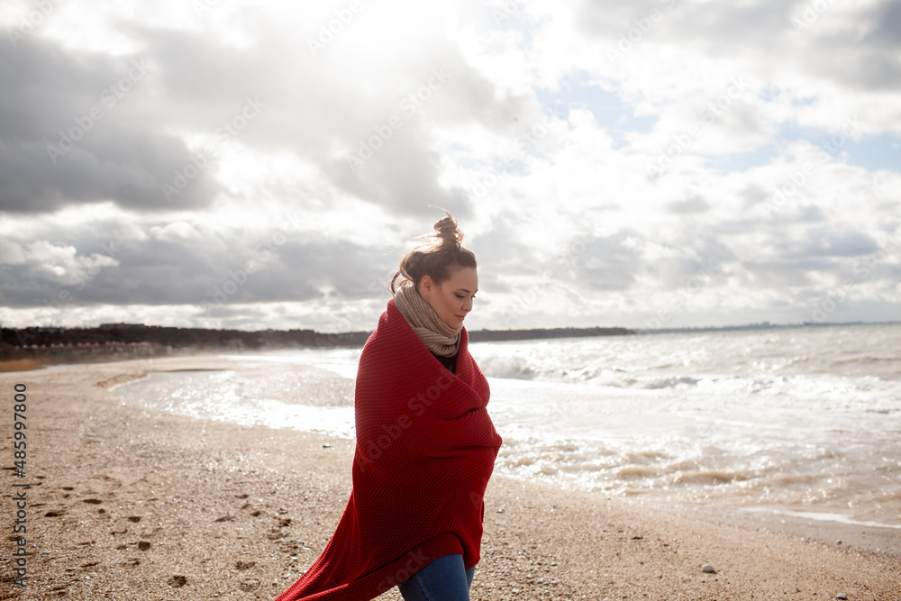 Beatuful woman with over weight body walking in the beach, The plus size model wearing jeans, the warm knitted blanket and sweater. the wind in the bich have fun with hairs Beatuful woman with over weight body walking in the beach, The plus size model wearing jeans, the warm knitted blanket and sweater. the wind in the bich have fun with hairs