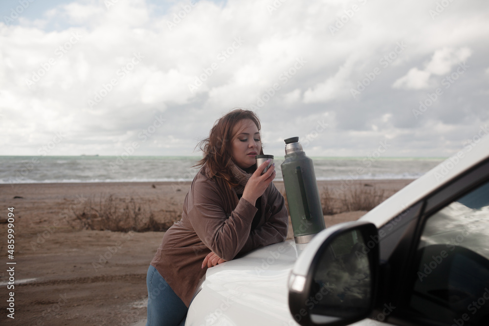 Beatuful woman with over weght body walking in the beach, The plus size model wearing jeans, the warm knitted blanket and sweater. the wind in the bich have fun with hairs. trip in the car