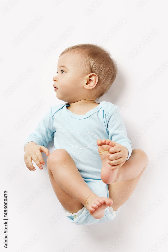 Little boy in romper lying on back and looking. Little boy in romper lying on back and looking.
