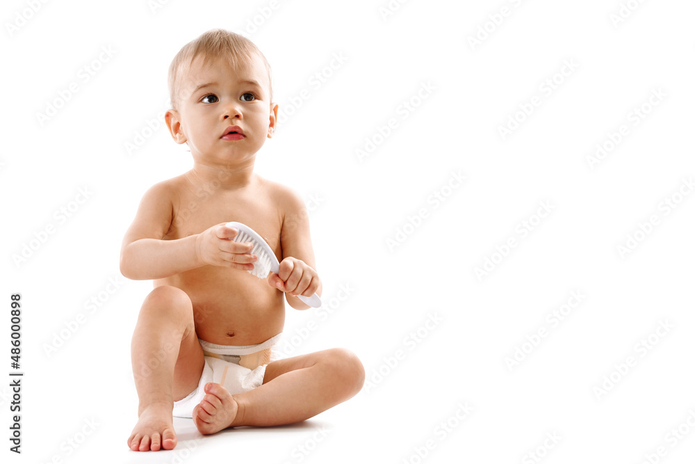 Little boy in diaper sitting and playing with brush. Little boy in diaper sitting and playing with brush.