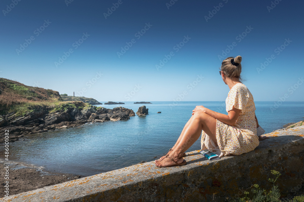 Woman sitting on embankment overlooking sea