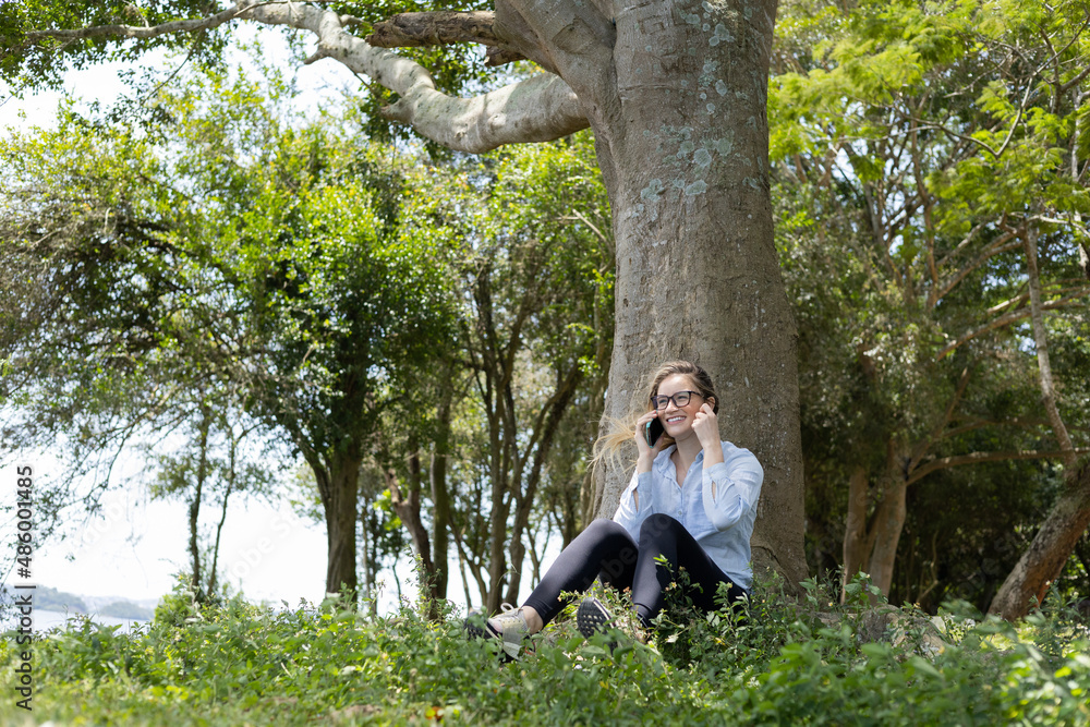 Young woman using a smartphone at day time with a green park in the background. High quality photo Young woman using a smartphone at day time with a green park in the background. High quality photo