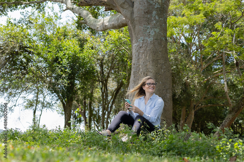 Young woman using a smartphone at day time with a green park in the background. High quality photo Young woman using a smartphone at day time with a green park in the background. High quality photo