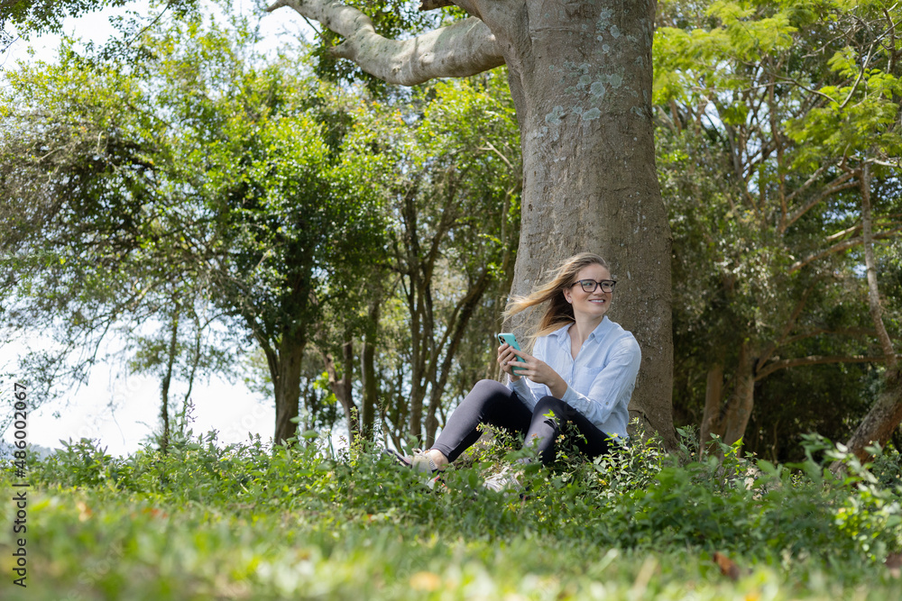 Young woman using a smartphone at day time with a green park in the background. High quality photo Young woman using a smartphone at day time with a green park in the background. High quality photo