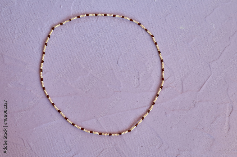 Handmade beadwork, beading as a hobby. Decorations made with your own hands on the background of various flowers Handmade beadwork, beading as a hobby. Decorations made with your own hands on the background of various flowers