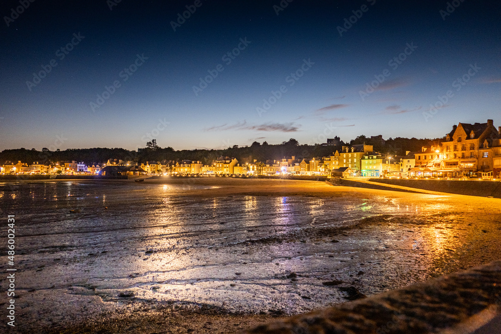 Illuminated cityscape by beach during sunset Illuminated cityscape by beach during sunset