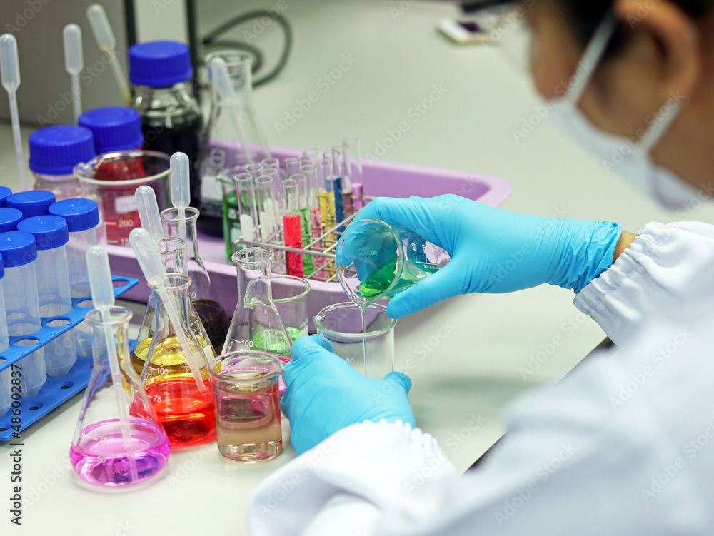 The scientist wears PPE do the chemical experiment in laboratory, with pale pink solvent solution from pouring reaction indicator acid titration experiment, analysis compounding in wastewater sample. The scientist wears PPE do the chemical experiment in laboratory, with pale pink solvent solution from pouring reaction indicator acid titration experiment, analysis compounding in wastewater sample.