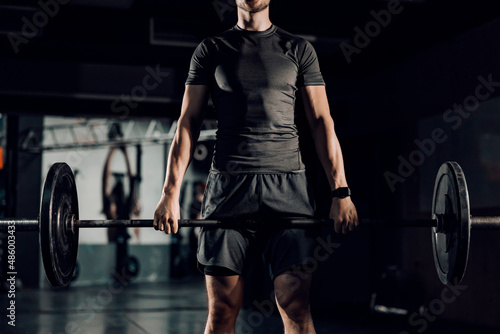 Unknown man practicing deadlift at the gym with barbell.