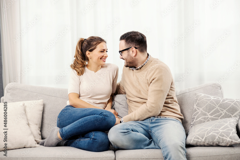 Happy couple talking on the sofa at their comfortable apartment.