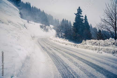 Snowy and icy road along a hill slope in bad weather.