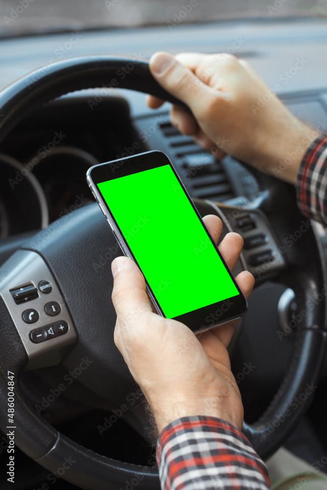 Vertical photo of millennial man hands holding mobile phone and using app with chroma key in car