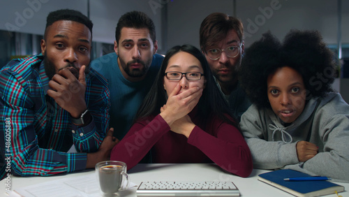 Multiethnic startup team looking at computer screen and getting shocked photo
