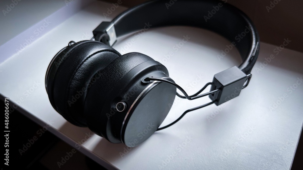 Modern black wireless headphones lay on white table. Close-up dj tool. Modern black wireless headphones lay on white table. Close-up dj tool.