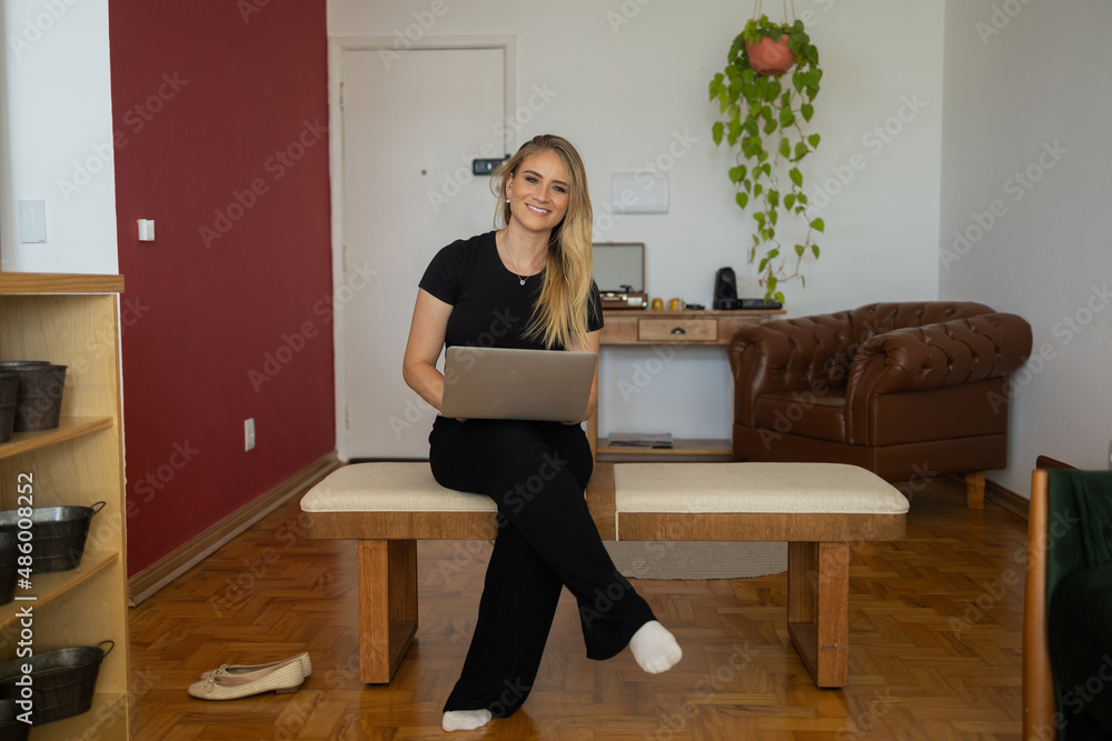 Young woman working at home from her living room couch with laptop on her lap. Home office concept. Young woman working at home from her living room couch with laptop on her lap. Home office concept.