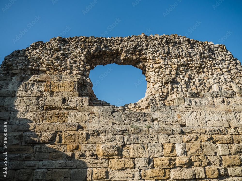 Ruins of an old fortress. Texture of an old brown brick wall. Irregularities. Opening under the window. Against the background of the blue sky.
