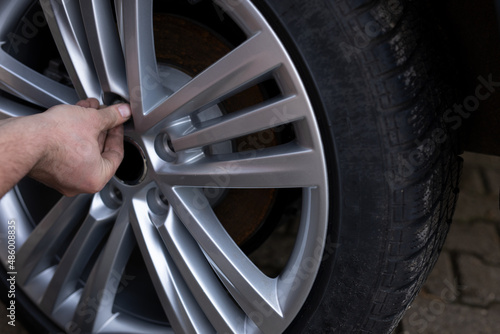 A close up of the man’s hands changing tires on the car