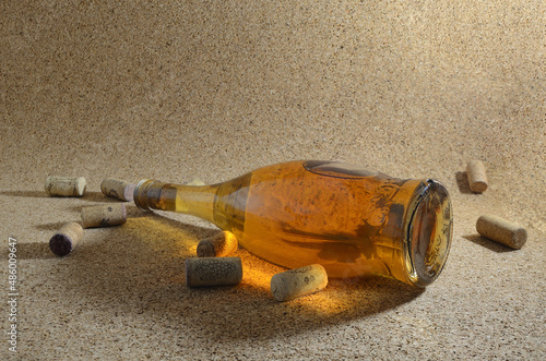 A bottle of homemade wine on a cork background, surrounded by spilled wine corks.