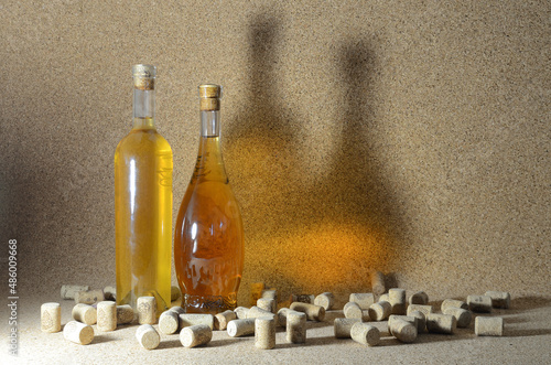 Two bottles of homemade wine on a cork background, surrounded by spilled wine corks.