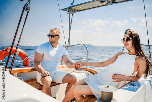 Young family couple who have romantic walk on the yacht and relaxing. Weekend at sea. Travel concept © zamuruev