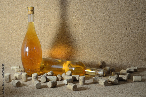 Two bottles of homemade wine on a cork background, surrounded by spilled wine corks.