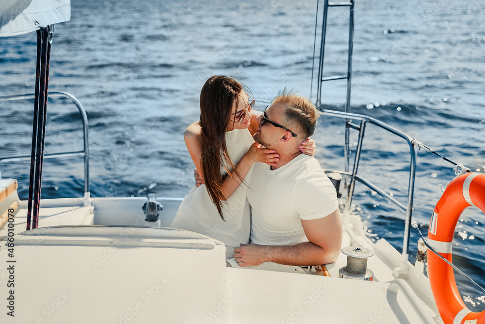 happy young couple who sitting together on yacht while looking to each other and kissing. Honeymoon 