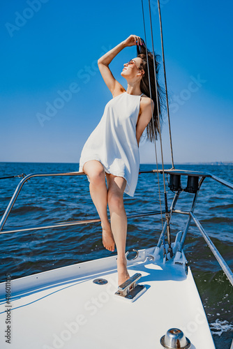 Beautiful young brunette woman in white dress enjoys walk on the yacht. Luxury resort Travel concept