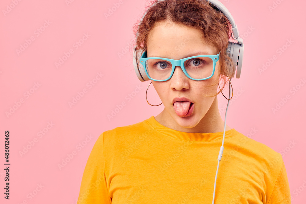 portrait of a young woman wearing blue glasses listening to music on headphones Lifestyle unaltered