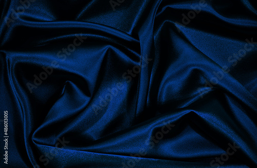 Black blue silk satin. Wavy folds. Shiny fabric surface. Elegant navy blye background with space for design. photo