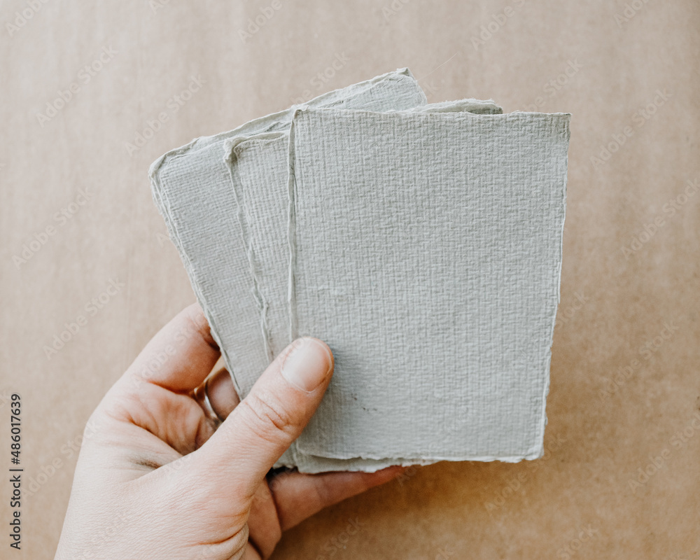 White Riggid Edge Hand holding white ragged edge art papers with brown paper wood blank ...