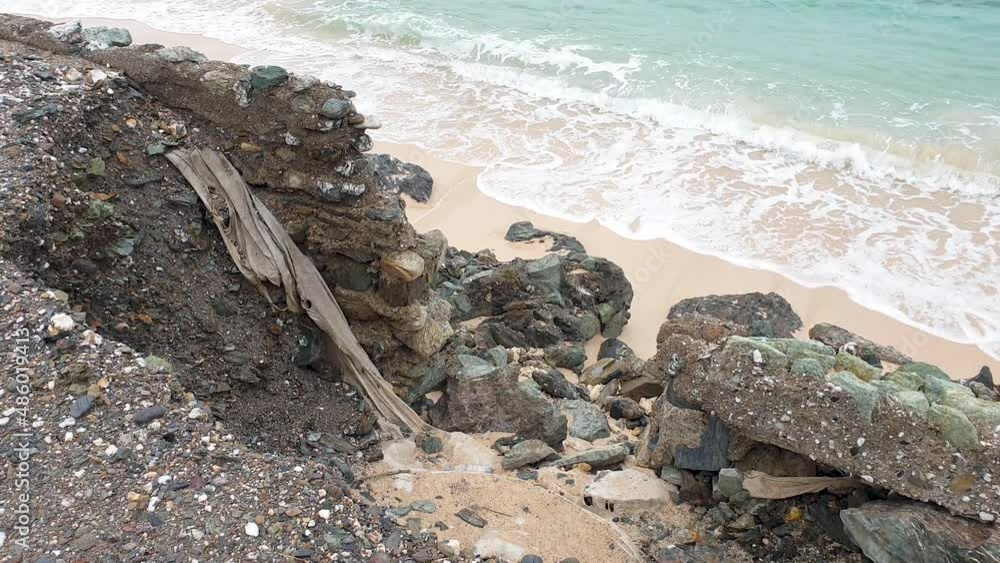 Ocean sea wall and road corrosion, collapsed due to impacts of rising tides, climate change, with waves gentle washing onto the beach Ocean sea wall and road corrosion, collapsed due to impacts of rising tides, climate change, with waves gentle washing onto the beach