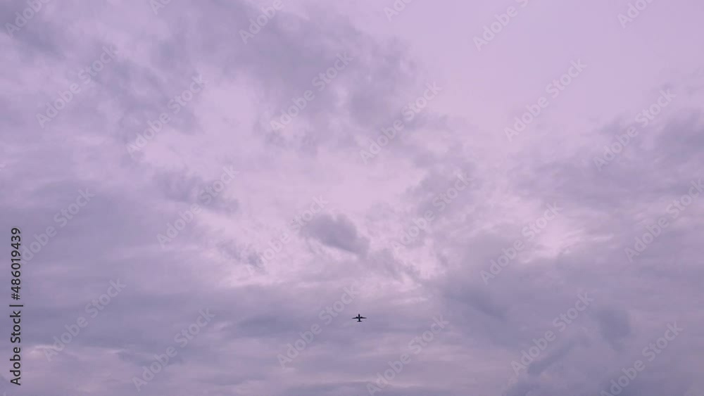 A silhouetted airplane flying with a stunning evening pink and purple cloudy evening sky, plane flies overhead from South East Asia A silhouetted airplane flying with a stunning evening pink and purple cloudy evening sky, plane flies overhead from South East Asia