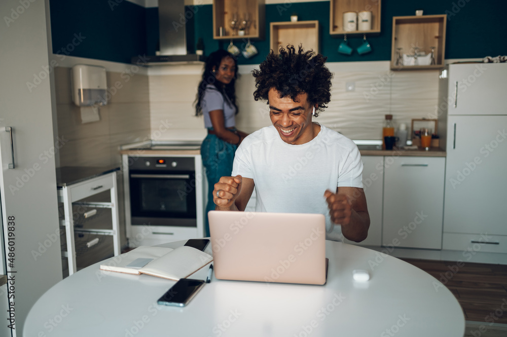 African american man using laptop in the kitchen at home African american man using laptop in the kitchen at home