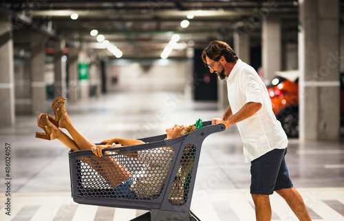 Fotografi Happy adult couple enjoy and have fun with shopping cart inside a commercial center mall garage