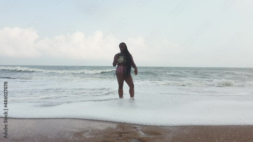 Woman with drone remote control in sea waves, Elmina, Ghana Woman with drone remote control in sea waves, Elmina, Ghana