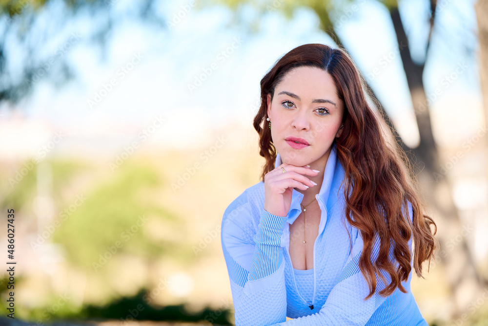 Young pretty woman with green eyes in blue dress sitting in the city park Young pretty woman with green eyes in blue dress sitting in the city park
