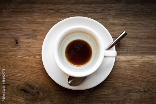 An overhead view of an empty cup of black coffee and a spoon, selective focus natural light image