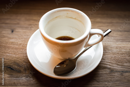 An empty cup of black coffee and a spoon  selective focus natural light image