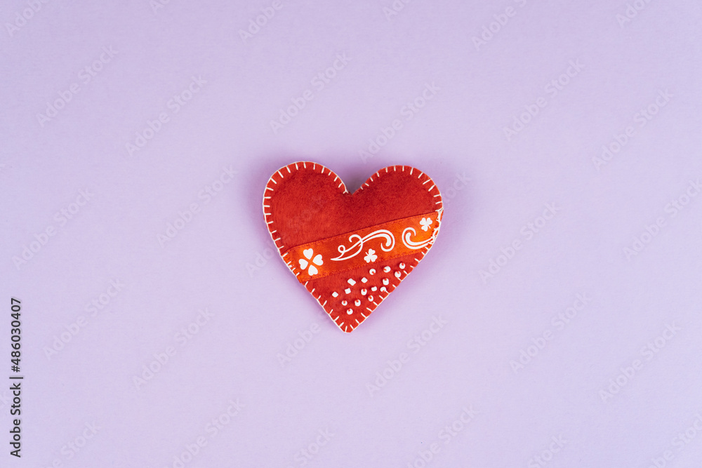 Top view Valentine's Day concept with copy space. Red textile heart on purple papper background